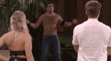 a man without a shirt is dancing in front of a woman and a man .