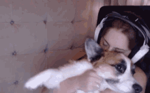 a woman wearing headphones holds a dog in her arms