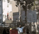 a man is sitting on a bench with his arms outstretched in front of a tree .