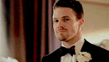 a man in a tuxedo with a bow tie and a flower in his lapel .