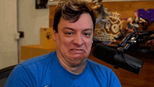 a man wearing a blue shirt is making a funny face in front of a microphone
