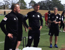 a group of men standing on a field with one wearing a red bulls jersey