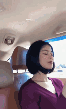 a woman in a purple sweater is sitting in the back seat of a car