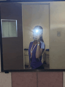 a woman in a purple shirt is taking a picture of herself in the mirror