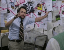 a man in a blue shirt and tie is pointing at a bulletin board with pepe evia written on it