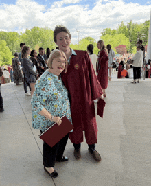 a woman stands next to a man in a graduation gown