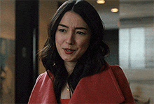 a woman wearing a red coat is making a funny face .