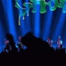a crowd of people are watching a stage show with a green liquid dripping from it