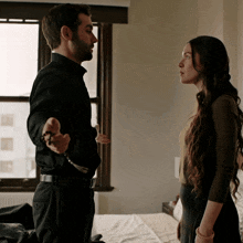 a man in a black shirt is holding a rosary and talking to a woman