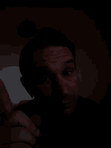 a man 's face is shown in a dark room with his eyes closed