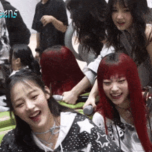 a girl with red hair is laughing while another girl holds a microphone in front of her