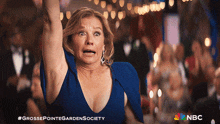 a woman in a blue dress holds up her arms in a grosse pointe garden society photo