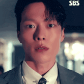 a close up of a man 's face with sbs written on the bottom