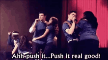 a group of people singing on a stage with the words push it real good