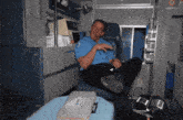 a man in a blue uniform is sitting in an ambulance with his feet up