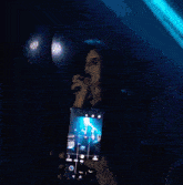 a woman is singing into a microphone while someone holds a cell phone