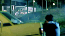 a yellow car is parked in front of a building with a sign that says ' hong kong ' on it