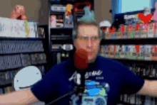 a man wearing a blue shirt that says a on it is talking into a microphone
