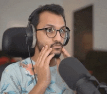 a man with a beard wearing headphones and glasses looks at the camera