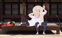 a couple of anime characters sitting on a wooden bench with watermelons in the background
