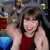 a woman in a red tank top is sitting in a chair and smiling .