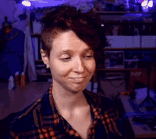 a woman in a plaid shirt is smiling in front of a shelf with n7 written on it