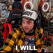 a man wearing a plaid shirt , headphones , and a hat is sitting in a chair .