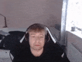 a man wearing headphones is sitting in a gaming chair in a room .