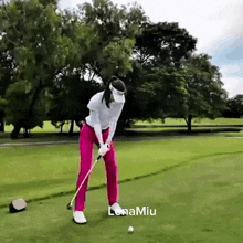 a woman is swinging a golf club on a golf course