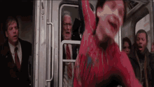 a man in a spiderman costume is jumping off a subway car .