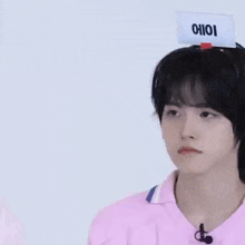 a close up of a person wearing a pink shirt and a headband with a sign on it .