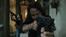a man with a tattoo on his arm is pointing a gun at another man