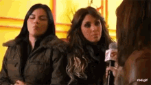 two women are standing next to each other and one is holding a microphone with the letter r on it