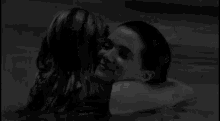 two women are kissing in a swimming pool at night .