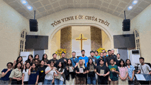 a group of people posing for a picture in front of a sign that says ton vinh e uc chua troi