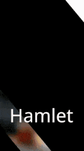 a man with a beard sits at a table with a cup of tea and the word hamlet on the bottom right