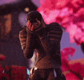 a man covering his face with his hands in front of a pink tree