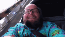 a bald man with glasses and a beard is smiling while riding a roller coaster