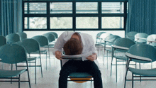 a man in a lab coat sits on a chair with his head on a piece of paper