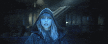 a woman wearing a hooded jacket is pointing at the camera