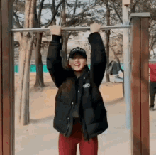 a woman is hanging upside down from a bar in a park .