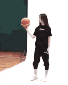 a young woman is holding a basketball in her hand .