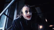 a close up of a man in a suit and tie with a joker face painted on his face .