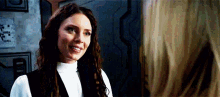 a woman is smiling at another woman while standing next to each other in a room .