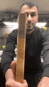 a man in a black sweater is holding a piece of gold