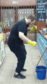a man wearing yellow rubber gloves is mopping the floor of a store