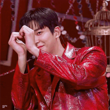 a man wearing a red jacket is making a heart shape with his hands