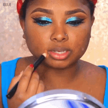 a woman is applying lip pencil to her lips while looking in a mirror .