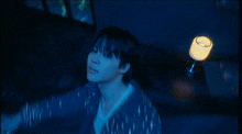 a blurry picture of a man in a dark room with a lamp in the background