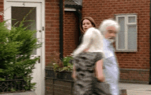 a man and a woman walking in front of a brick building